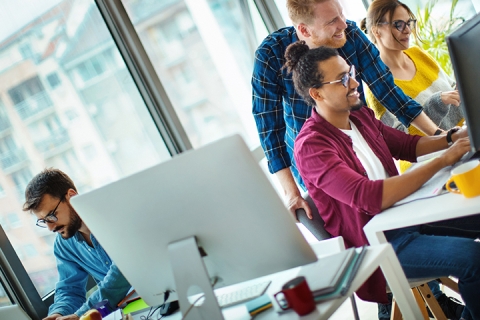 Closeup side view of a small multi ethnic team of young adults engaged in software application development.