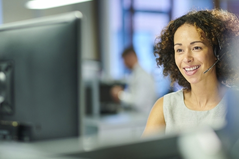 Woman working at her computer and on a call with a customer