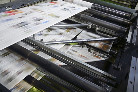 Printing press machine printing broadsheet newspapers in a printing plant.