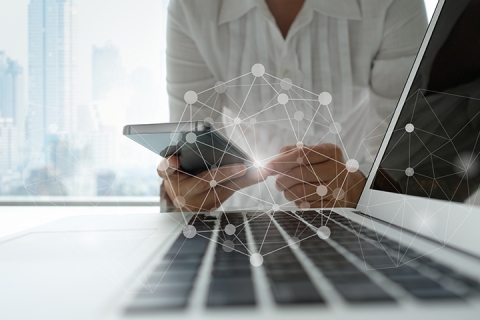 Wireless network icon in front of business person using smartphone and laptop