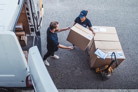 Delivery workers using a Hydraulic Hand Pallet Truck to load a delivery van.