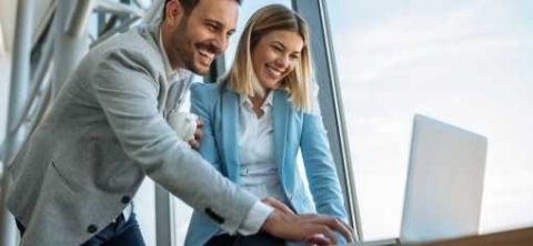 2 coworkers smiling looking at a computer