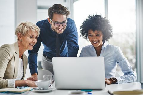 Three coworkers looking at a computer