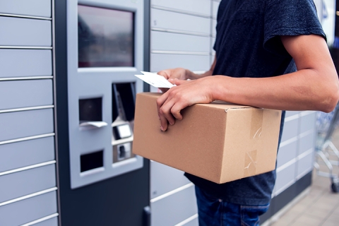 person using parcel locker while holding package