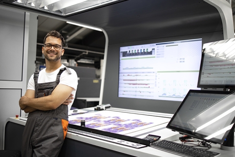 employee standing in front of printing machinery