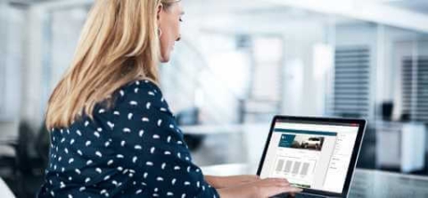 a blond woman working on a laptop showing quadient impress portal