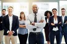 Portrait of a mature businessman standing in an office with his colleagues in the background