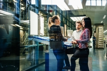 A team of engineers having a discussion at a desk in a large printing factory.