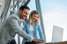 Happy employees smiling while working on laptop together