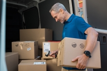 Courier holding parcel and scanning barcode with barcode reader in van