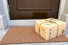 Parcel box wrapped in craft paper on the door mat near the entrance door