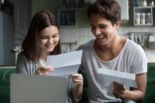 Happy young couple excited by reading good news in paper letter